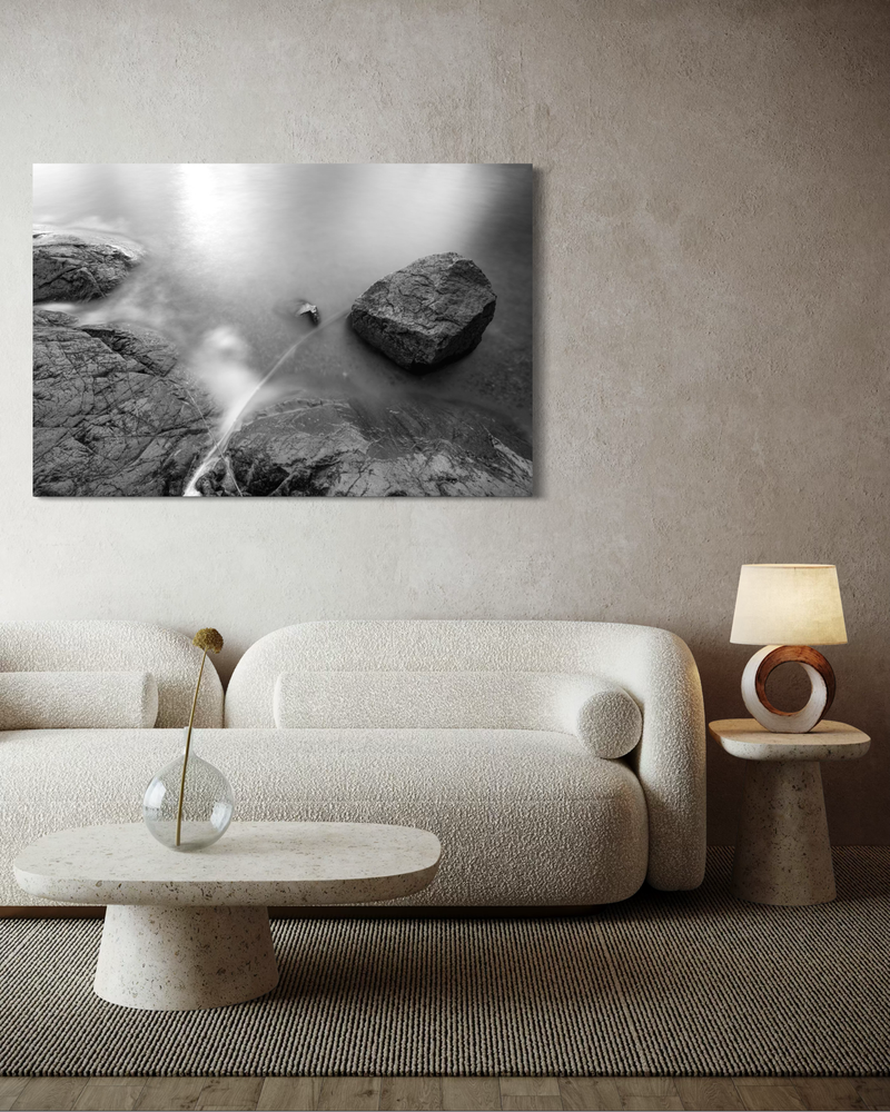 Zwart-wit fotografie op canvas van kliffen en oceaan met lange belichting, waarbij het water zacht rond de rotsen stroomt in een serene compositie.